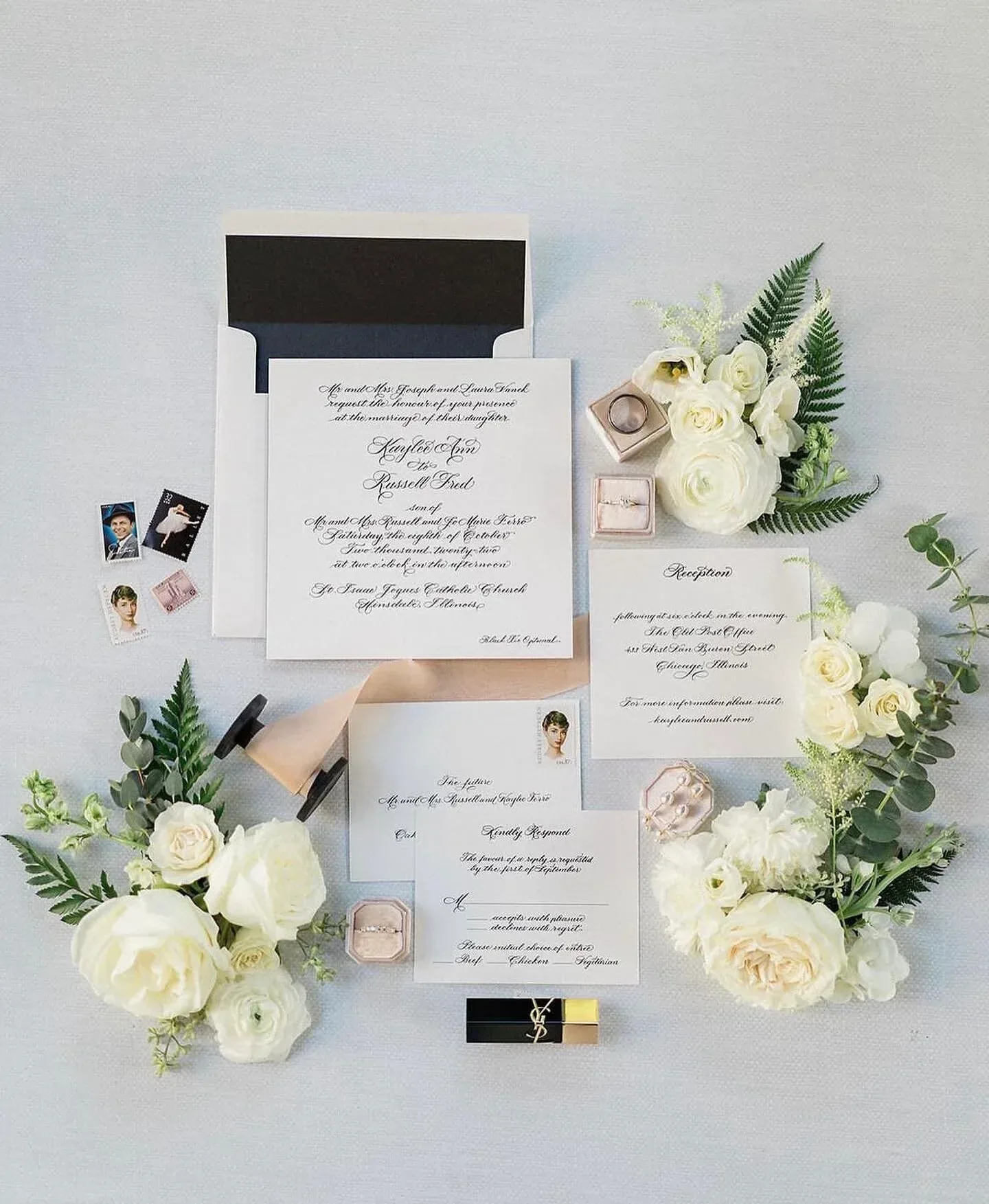 Calligraphy wedding invitation with a black-lined envelope and white florals